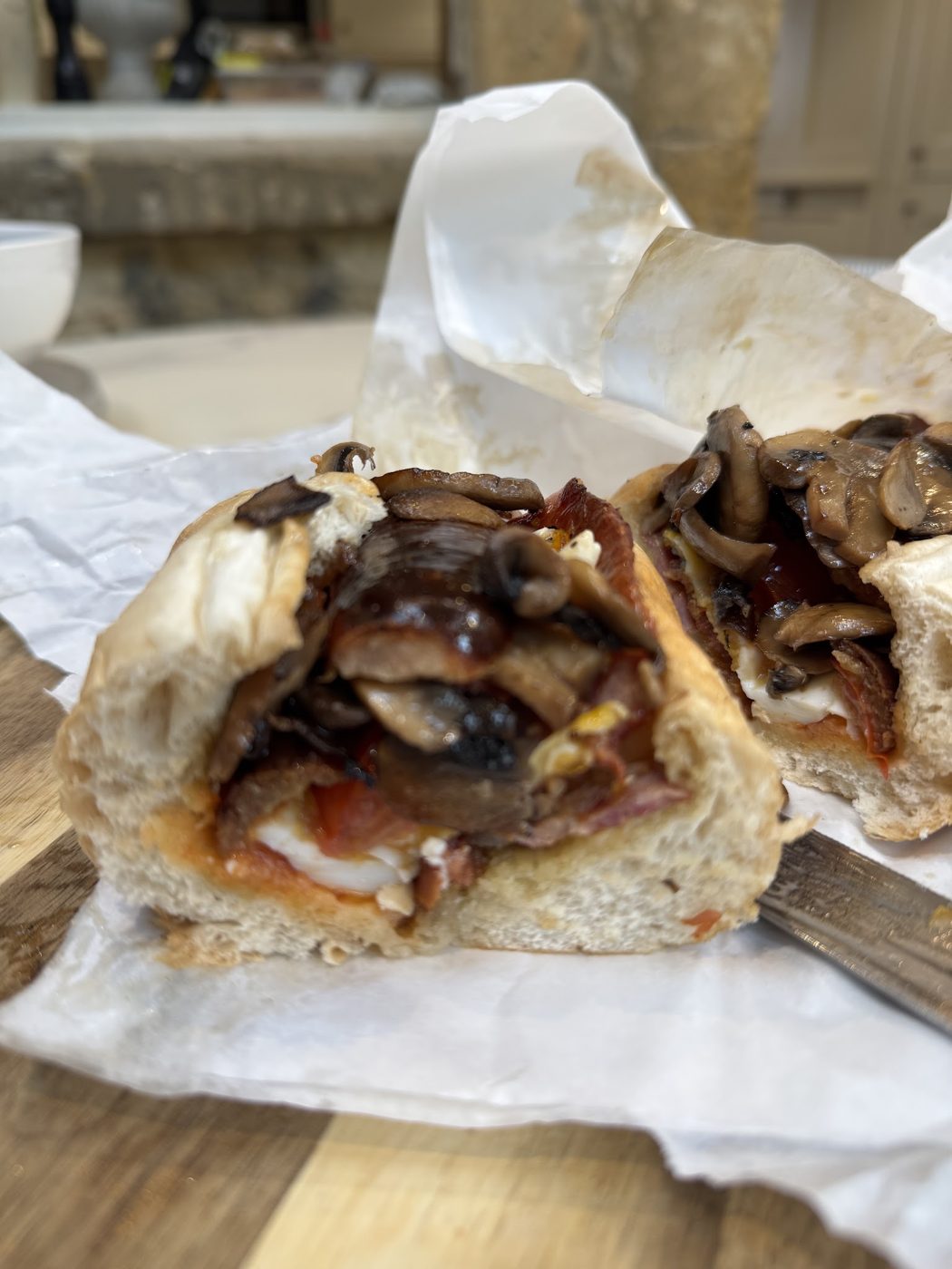 A baguette filled with mushrooms and onions in paper