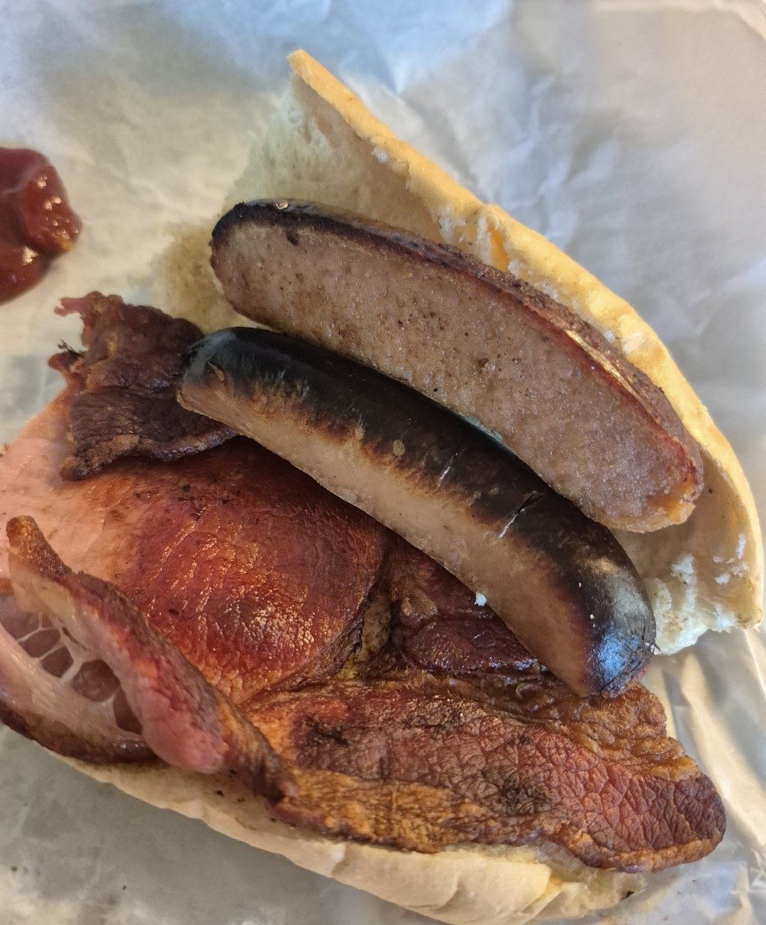 A roll with sausages and bacon in paper